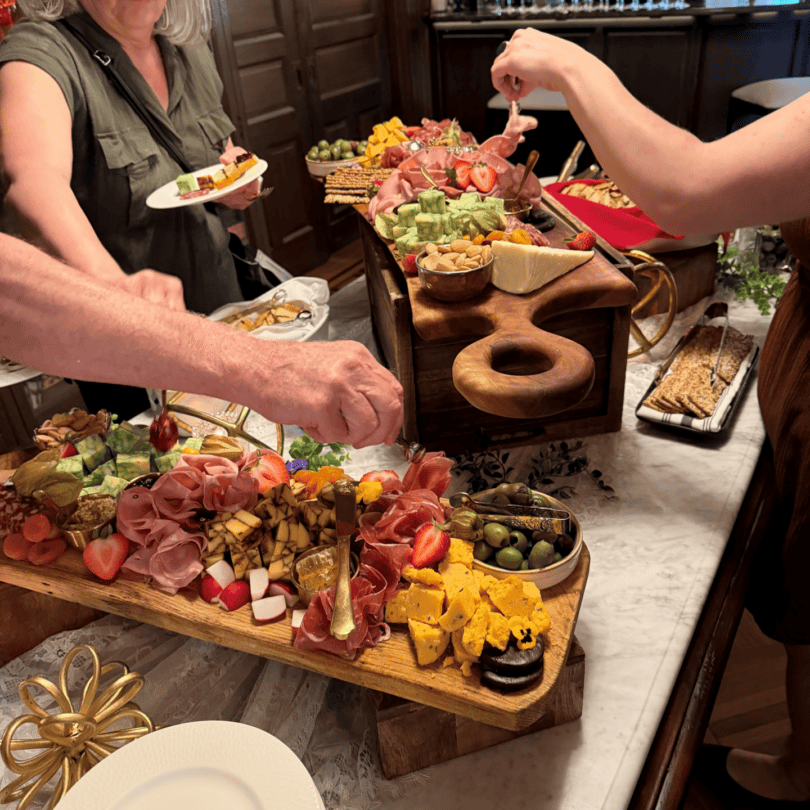 Hands reaching toward abundant charcuterie and cheeses